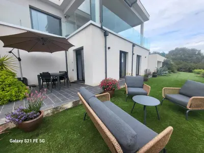a patio with chairs and a table and an umbrella at Villa Panoramique in Alata