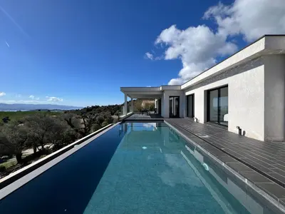 a swimming pool in front of a house at Villa Panoramique in Alata