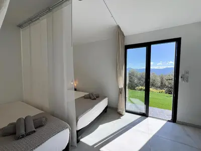 a bedroom with two beds and a large window at Villa Panoramique in Alata