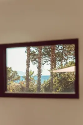 a picture of a window with trees and the ocean at Elegant Designer Home By The Sea In Corsica in Taglio-Isolaccio