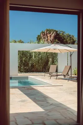 a pool with two chairs and an umbrella at Elegant Designer Home By The Sea In Corsica in Taglio-Isolaccio