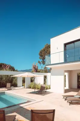 a white house with a swimming pool and chairs at Elegant Designer Home By The Sea In Corsica in Taglio-Isolaccio