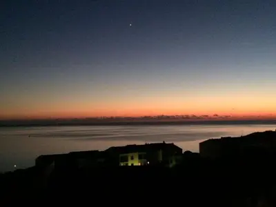 a sunset over the water with a house in the foreground at Location corsica in Ajaccio