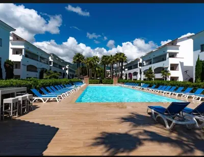 a swimming pool with blue lounge chairs and buildings at Amikad'o in San-Nicolao