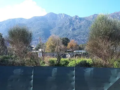 a view of a mountain range with trees and a fence at Villa en Corse sur la Côte Est in Santa-Maria-Poggio