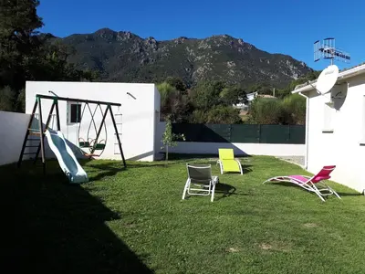 a yard with chairs and a swing set on the grass at Villa en Corse sur la Côte Est in Santa-Maria-Poggio