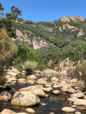 two people standing on rocks in a river at Appartement T2 vue mer sur le port de Solenzara in Kamiesch