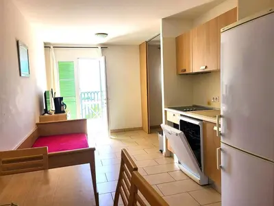 a kitchen with a refrigerator and a table and a kitchen with a stove at Appartement T2 vue mer sur le port de Solenzara in Kamiesch