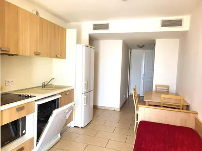 a kitchen with a table and a white refrigerator at Appartement T2 vue mer sur le port de Solenzara in Kamiesch