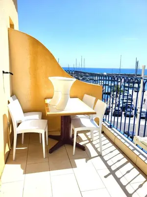 a table and chairs on a balcony with a view at Appartement T2 vue mer sur le port de Solenzara in Kamiesch
