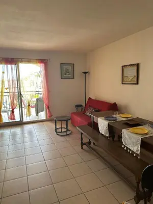 a living room with a red couch and a table at CASA LOUNA 2 Pièces à 150 m de la plage et du centre vile in Sari Solenzara