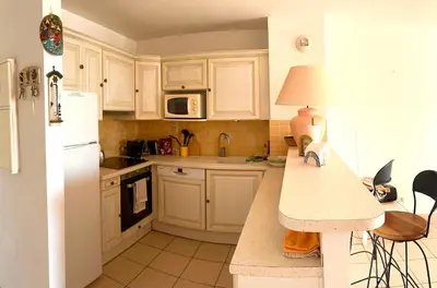 a kitchen with white cabinets and a white refrigerator at CASA LOUNA 2 Pièces à 150 m de la plage et du centre vile in Sari Solenzara