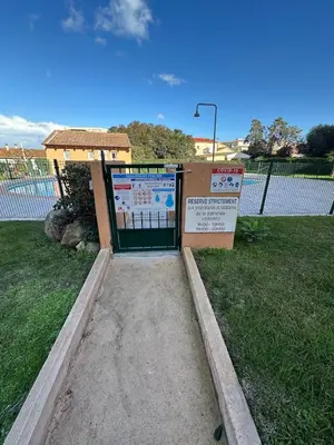 a gate with a sign in front of a building at CASA LOUNA 2 Pièces à 150 m de la plage et du centre vile in Sari Solenzara