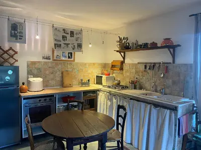 a kitchen with a wooden table and a table and a tableablish at Maison de village 3 chambres 2 SDB avec terrasse & jardin - Proche St Florent in Pieve