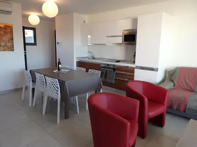 a kitchen and dining room with a table and red chairs at Appartement Cité Du Sel in Porto-Vecchio