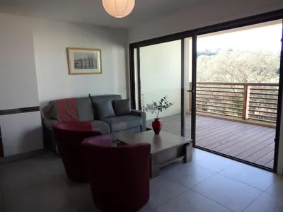 a living room with a couch and a table and a balcony at Appartement Cité Du Sel in Porto-Vecchio
