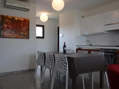 a kitchen with a table and chairs with a bottle of wine at Appartement Cité Du Sel in Porto-Vecchio