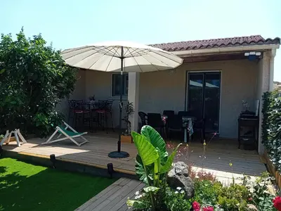 a wooden deck with an umbrella in a yard at Villa de luxe en bord de mer Résidence Torra Mare a Prunete in Cervione