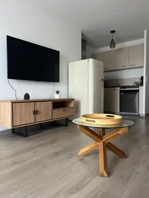 a living room with a table and a refrigerator at Appartement plus place de parking en sous sol privatif in Ajaccio