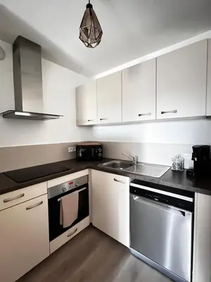 a kitchen with white cabinets and stainless steel appliances at Appartement plus place de parking en sous sol privatif in Ajaccio