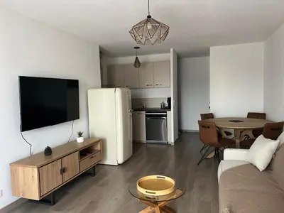 a living room with a white refrigerator and a table at Appartement plus place de parking en sous sol privatif in Ajaccio