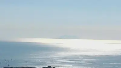 a large body of water with a mountain in the background at Villa Petrera in Valle-di-Campoloro