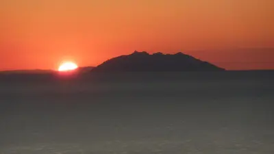 a sunset over the ocean with a mountain in the background at Villa Petrera in Valle-di-Campoloro