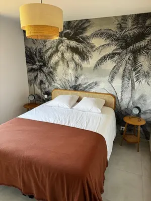 a bedroom with a bed with a palm mural at Bel appartement T3 vue mer 5 min des plages à pied in Propriano