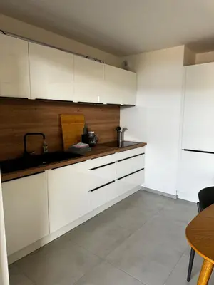 a kitchen with white cabinets and a table at Bel appartement T3 vue mer 5 min des plages à pied in Propriano