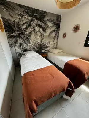 a bedroom with two beds and a palm mural at Bel appartement T3 vue mer 5 min des plages à pied in Propriano