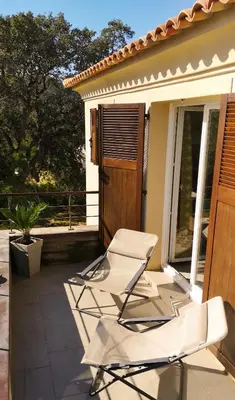 two white chairs on a patio with a house at un gout de paradis in Zonza