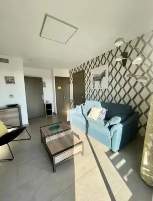 a living room with a blue couch and a table at un gout de paradis in Zonza