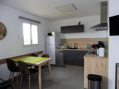 a small kitchen with a table and a table and chairs at un gout de paradis in Zonza