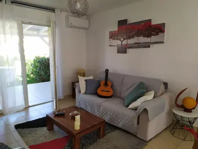 a living room with a couch and a guitar at Mini villa T2, 200 m de la plage, piscine chauffée, jardin in Prunete