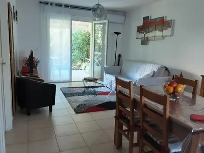 a living room with a table and a couch at Mini villa T2, 200 m de la plage, piscine chauffée, jardin in Prunete
