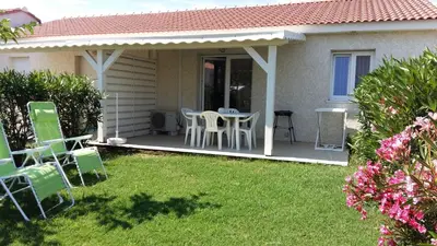 a patio with chairs and a table in a yard at Mini villa T2, 200 m de la plage, piscine chauffée, jardin in Prunete