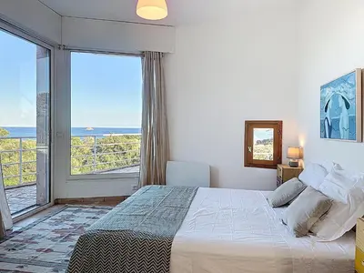 a bedroom with a bed and a view of the ocean at Villa Mimosa 150 m from Pinarello Beach in Zonza