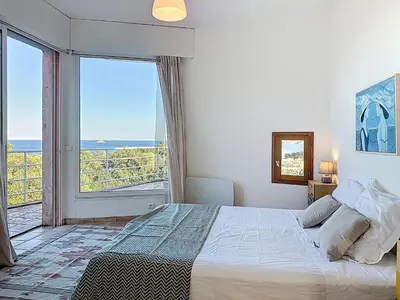 a bedroom with a bed with a view of the ocean at Villa Mimosa 150 m from Pinarello Beach in Zonza
