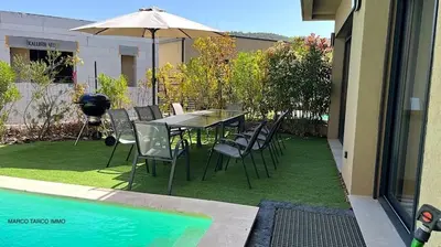 a table with chairs and an umbrella next to a pool at Villa Favone 3 in Favone