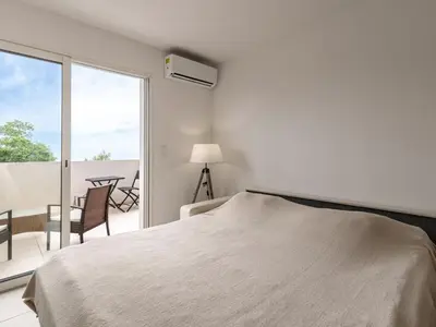 a white bedroom with a bed and a balcony at Studio Brigitte by Interhome in Linguizzetta