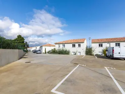 a parking lot with a white building and a van at Studio Brigitte by Interhome in Linguizzetta