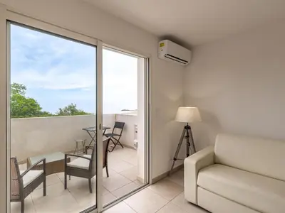 a living room with a couch and a table and a balcony at Studio Brigitte by Interhome in Linguizzetta