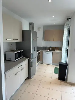a kitchen with white cabinets and a stainless steel refrigerator at Appart, résidentiel penta-di-Casinca in Penta-di-Casinca