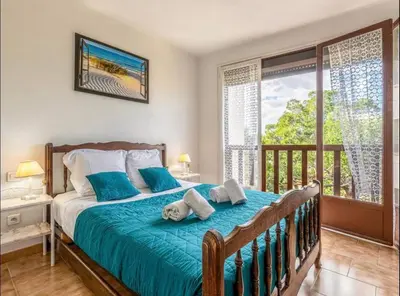 a bedroom with a bed with blue sheets and a balcony at Appartamentu Soli di Sud - St Cyprien in Lecci