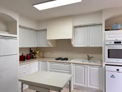 a white kitchen with white cabinets and a table at Appartamentu Soli di Sud - St Cyprien in Lecci