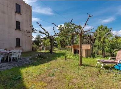 a garden with a table and chairs and a grill at Appartamentu Soli di Sud - St Cyprien in Lecci