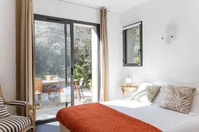 a bedroom with a bed and a sliding glass door at Belle villa 3 chambres au cœur du maquis in Porto-Vecchio