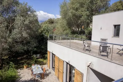 a balcony of a house with a table and chairs at Belle villa 3 chambres au cœur du maquis in Porto-Vecchio