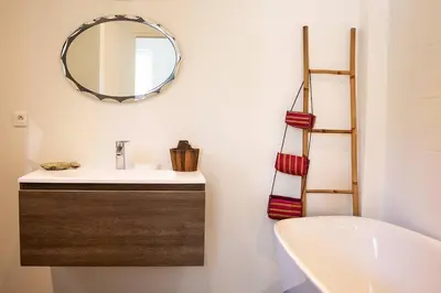 a bathroom with a sink and a mirror and a tub at Belle villa 3 chambres au cœur du maquis in Porto-Vecchio