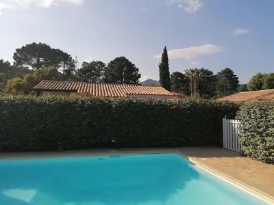 a blue swimming pool in front of a hedge at villa dans petite résidence avec piscine à 10 minutes des plages proche PORTO VECCHIO in Porto-Vecchio
